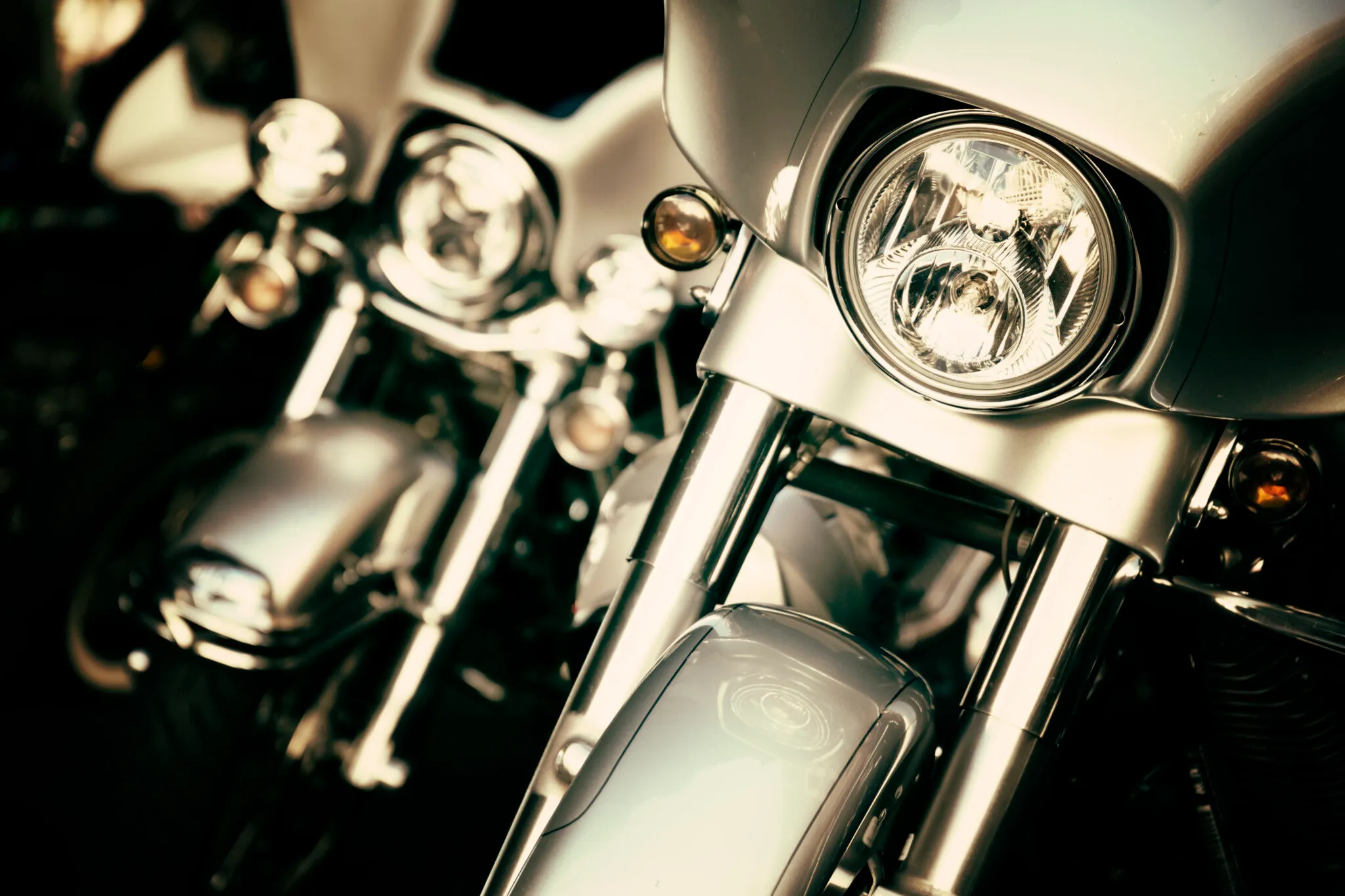 Close-up of the chrome headlight and front forks of a silver motorcycle