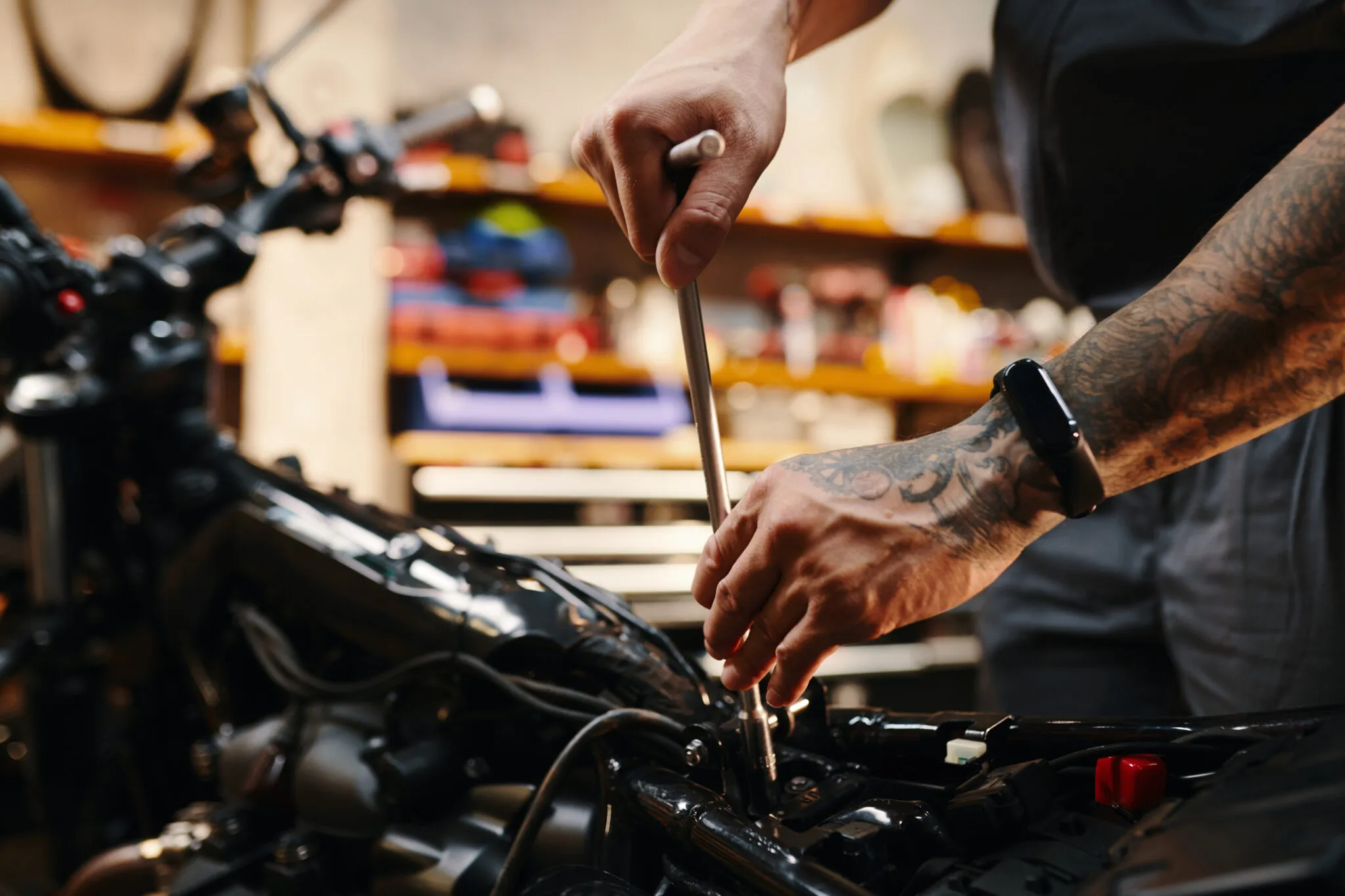 Mechanic working on a motorcycle engine with a wrench in a workshop