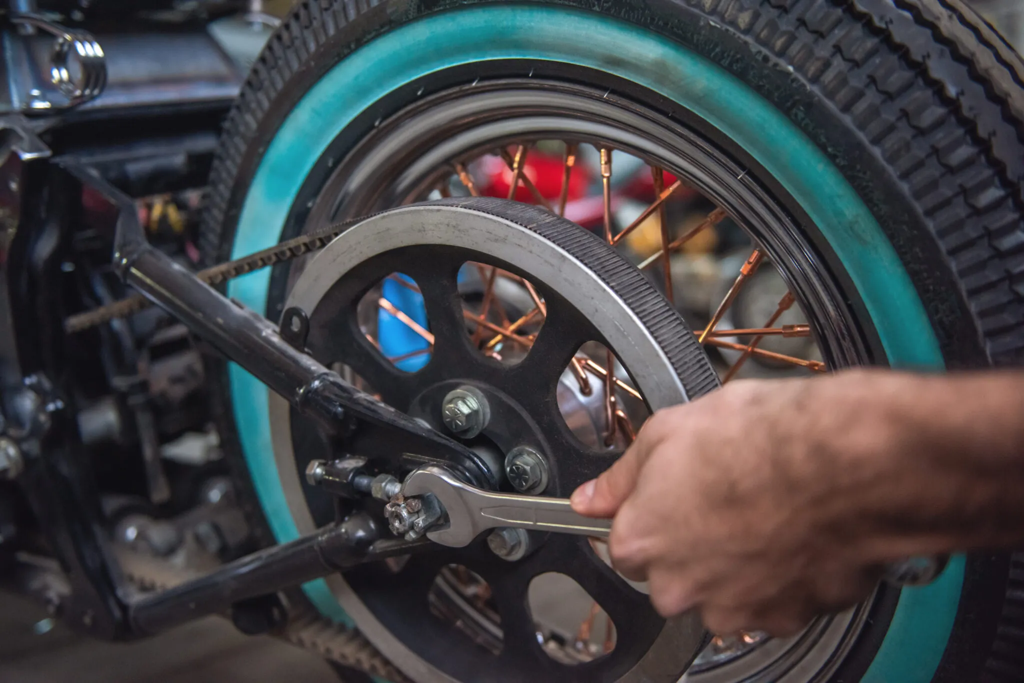 Mechanic tightening the rear wheel of a motorcycle with a wrench